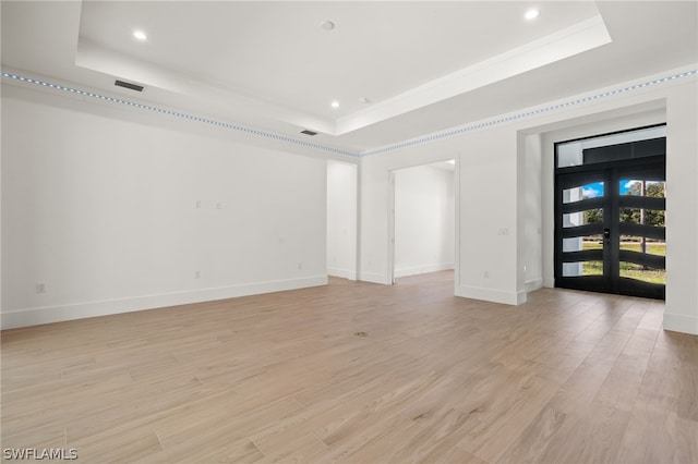 spare room featuring french doors, light wood-type flooring, and a tray ceiling