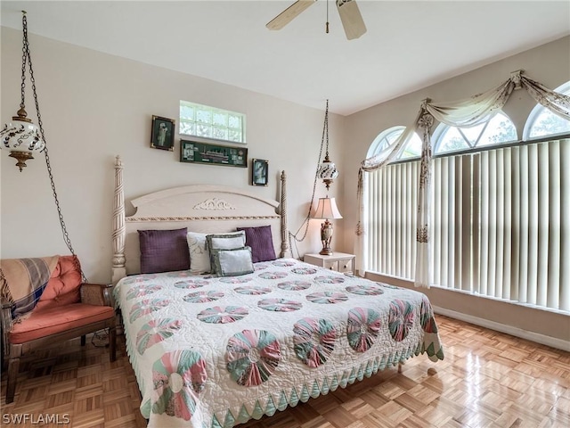 bedroom with ceiling fan, parquet floors, and multiple windows