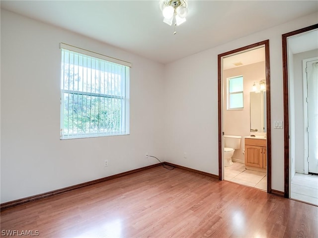 unfurnished bedroom with light hardwood / wood-style flooring and ensuite bath