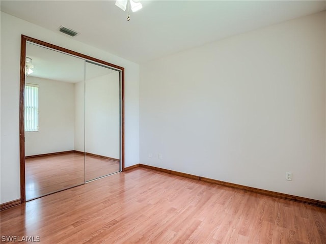 unfurnished bedroom featuring ceiling fan, a closet, and light wood-type flooring