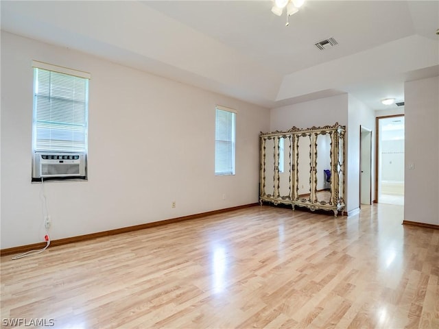 unfurnished room featuring cooling unit, a raised ceiling, and light hardwood / wood-style floors