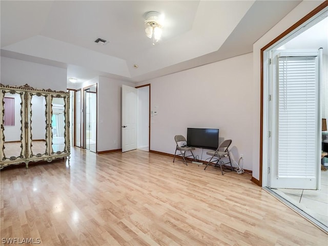 interior space with light hardwood / wood-style flooring and a raised ceiling