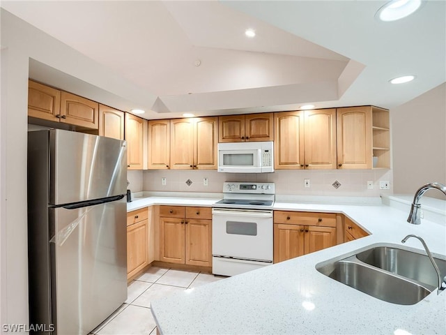 kitchen featuring light brown cabinets, white appliances, sink, light tile patterned flooring, and kitchen peninsula