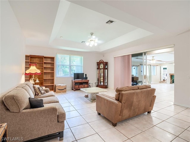 tiled living room featuring a raised ceiling and ceiling fan