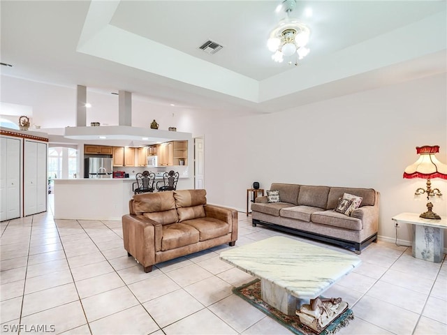 tiled living room with a tray ceiling and ceiling fan