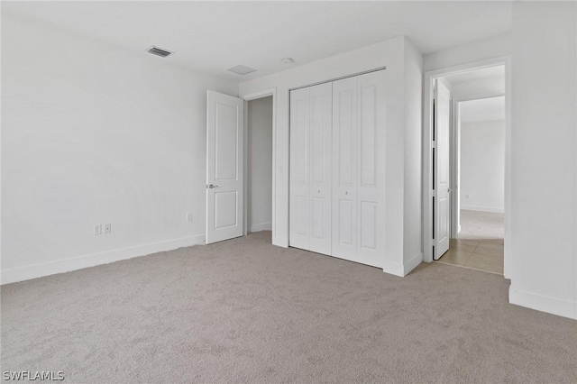 unfurnished bedroom featuring light carpet and a closet