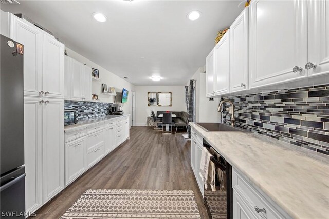 kitchen with black appliances, sink, dark wood-type flooring, and white cabinetry