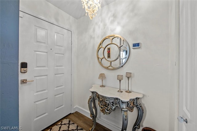 foyer entrance with baseboards, dark wood-type flooring, and an inviting chandelier