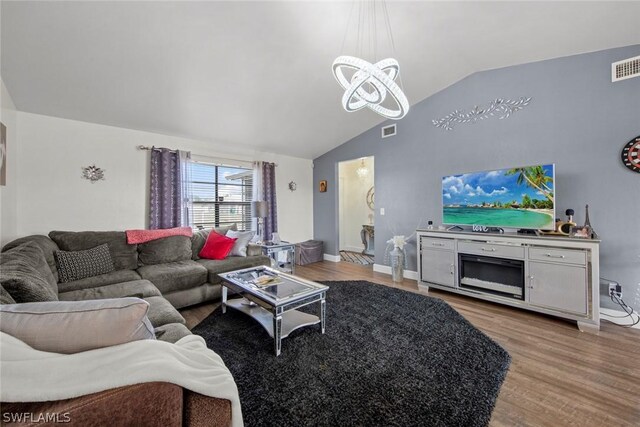 living room featuring an inviting chandelier, light wood-type flooring, and lofted ceiling