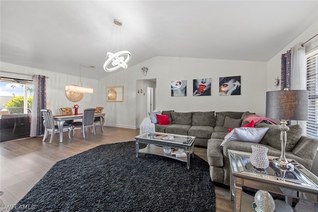 living room featuring lofted ceiling, an inviting chandelier, and light hardwood / wood-style flooring