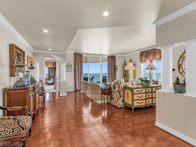 living room with ornate columns, plenty of natural light, a water view, and ornamental molding