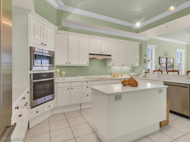 kitchen with white cabinets, a kitchen island, light tile patterned floors, and appliances with stainless steel finishes