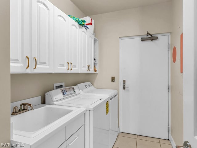 washroom with cabinets, light tile patterned floors, sink, and washing machine and clothes dryer