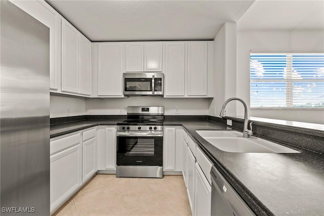 kitchen with white cabinetry, stainless steel appliances, sink, and light tile patterned floors