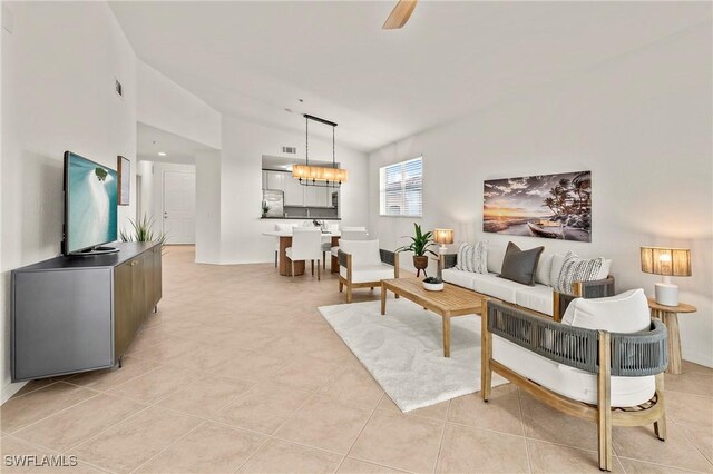 living room featuring ceiling fan with notable chandelier, vaulted ceiling, and light tile patterned flooring