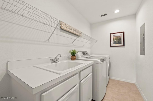 washroom with light tile patterned flooring, sink, cabinets, electric panel, and washing machine and dryer