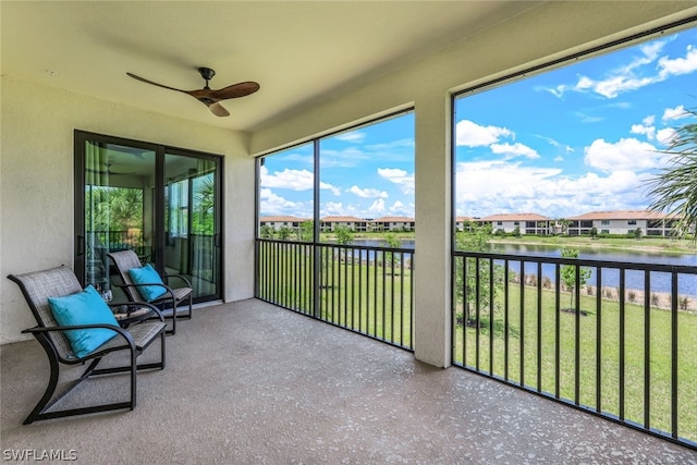 unfurnished sunroom featuring ceiling fan and a water view