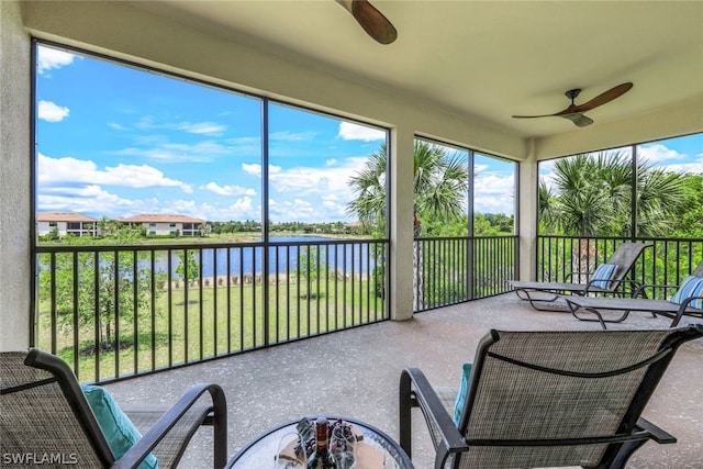 sunroom with ceiling fan and a water view