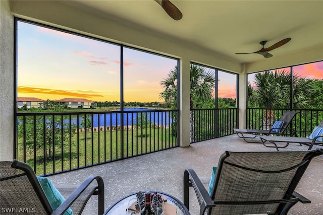 sunroom / solarium featuring ceiling fan and a water view