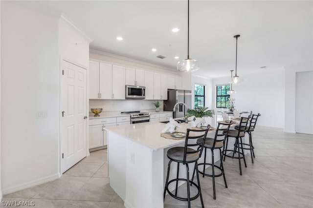 kitchen with a center island with sink, white cabinets, sink, decorative light fixtures, and stainless steel appliances