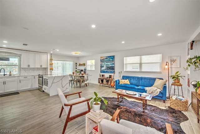 living room featuring light hardwood / wood-style flooring, a healthy amount of sunlight, and sink