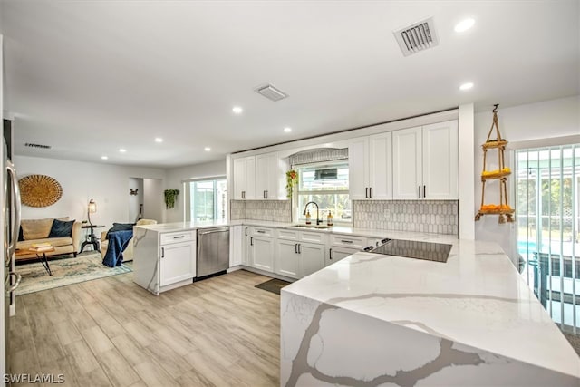 kitchen featuring dishwasher, tasteful backsplash, kitchen peninsula, and light hardwood / wood-style flooring