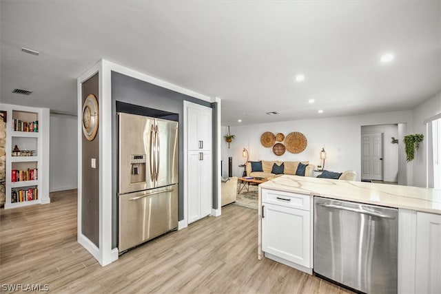 kitchen featuring light stone counters, light wood-type flooring, white cabinetry, and stainless steel appliances