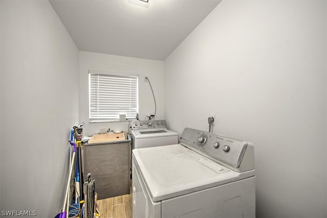 laundry area with separate washer and dryer and light hardwood / wood-style flooring