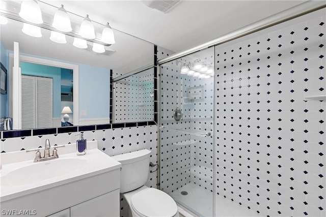 bathroom with tasteful backsplash, vanity, a shower with door, tile walls, and toilet