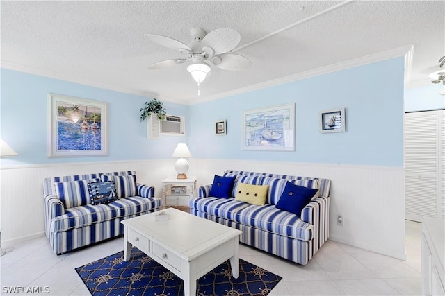 living room featuring ceiling fan, light tile patterned flooring, ornamental molding, and a textured ceiling