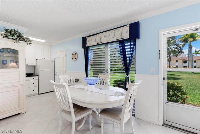 tiled dining room with a textured ceiling, a wealth of natural light, and ornamental molding