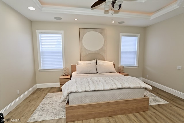 bedroom with ceiling fan, a raised ceiling, multiple windows, and hardwood / wood-style floors