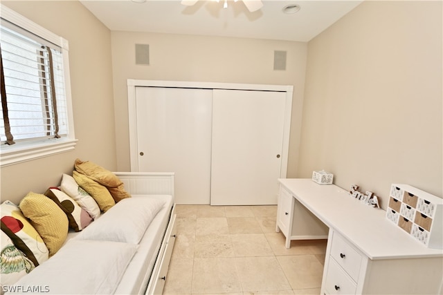 tiled bedroom with ceiling fan and a closet