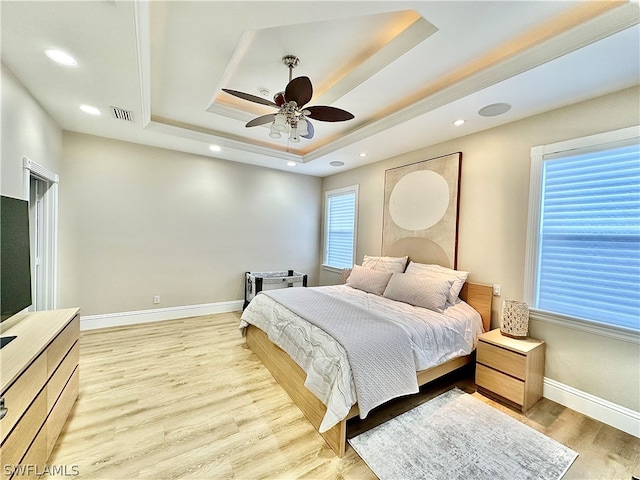 bedroom featuring hardwood / wood-style floors, ceiling fan, and a raised ceiling