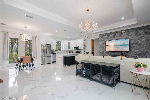 living room with a raised ceiling, ornamental molding, and a chandelier