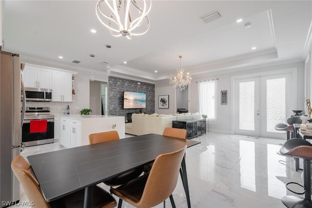 dining space with a chandelier, french doors, a raised ceiling, and ornamental molding