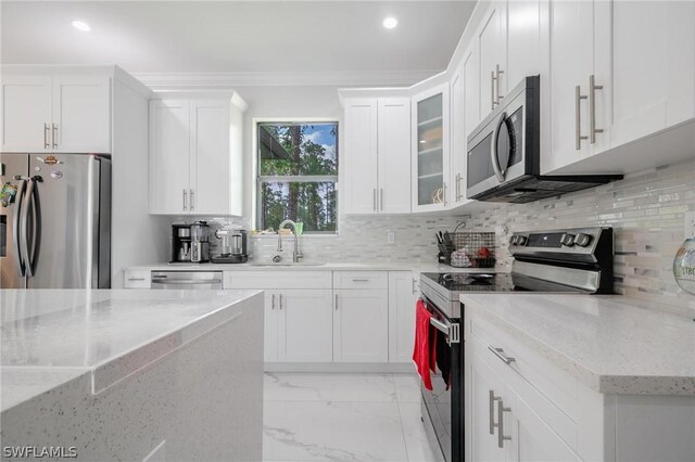 kitchen with light stone countertops, appliances with stainless steel finishes, backsplash, and white cabinetry