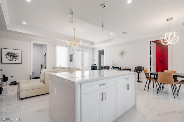 kitchen with white cabinets, a tray ceiling, hanging light fixtures, and a notable chandelier