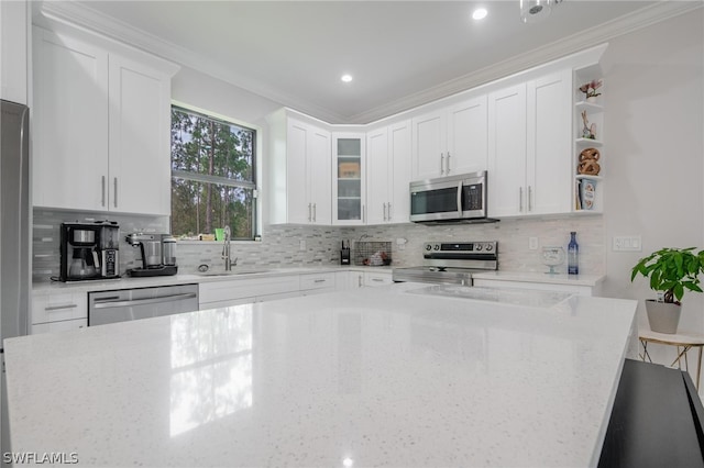 kitchen with white cabinets, appliances with stainless steel finishes, ornamental molding, and sink