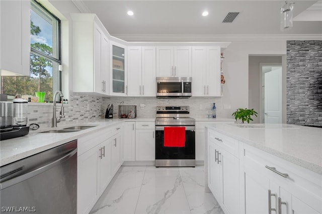 kitchen with white cabinetry, crown molding, appliances with stainless steel finishes, and tasteful backsplash