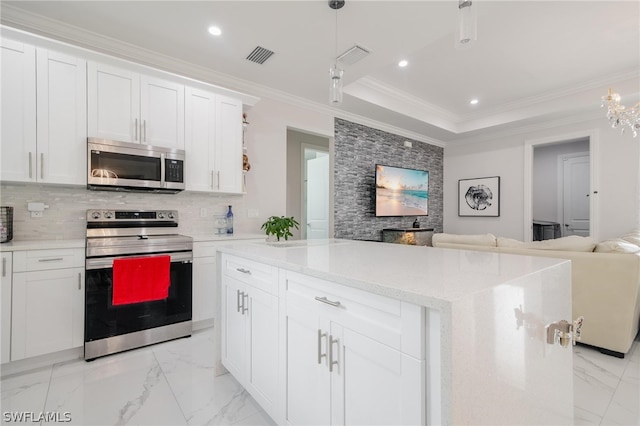 kitchen featuring backsplash, stainless steel appliances, white cabinetry, and hanging light fixtures