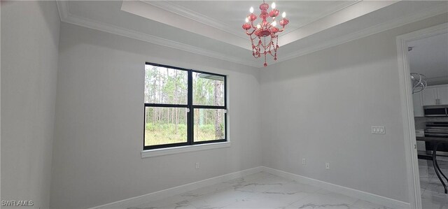 empty room with a chandelier, ornamental molding, and a tray ceiling