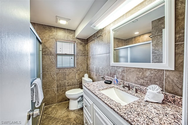 bathroom with vanity, toilet, tile walls, and walk in shower