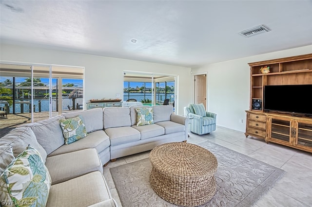 tiled living room featuring a wealth of natural light and a water view