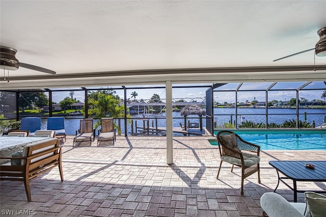 view of patio featuring a lanai, ceiling fan, and a water view