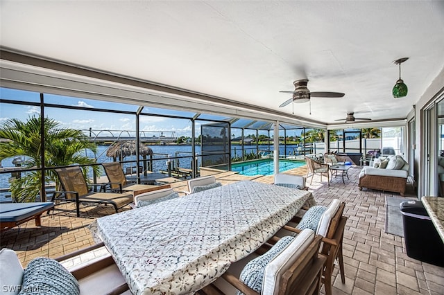 sunroom with ceiling fan and a water view