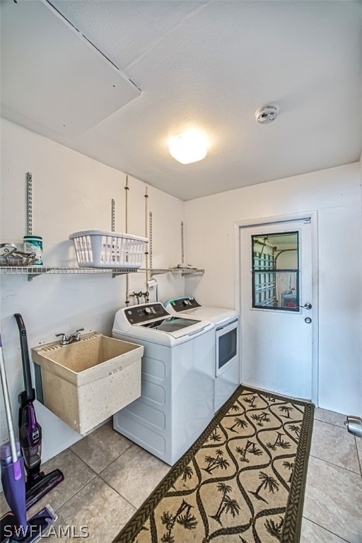 clothes washing area featuring light tile patterned flooring, independent washer and dryer, and sink