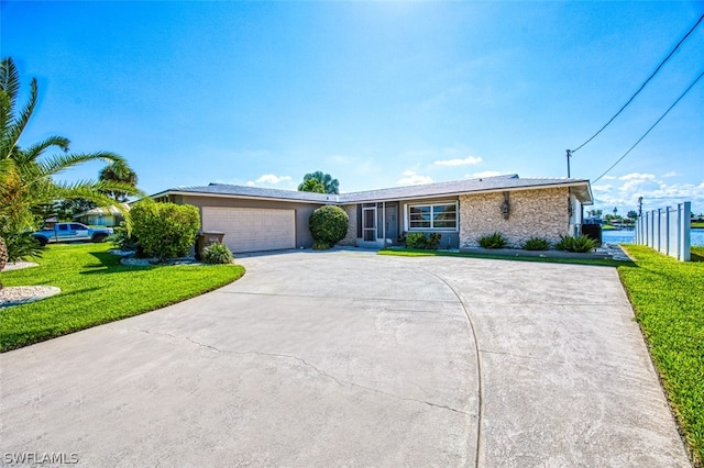 ranch-style house featuring a garage, a water view, and a front lawn