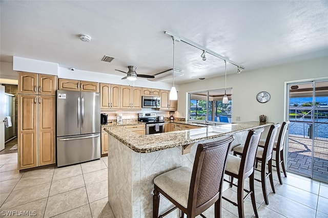 kitchen featuring pendant lighting, a breakfast bar, track lighting, appliances with stainless steel finishes, and kitchen peninsula