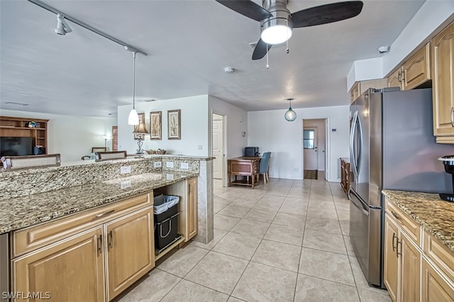 kitchen with pendant lighting, track lighting, ceiling fan, light stone counters, and stainless steel refrigerator